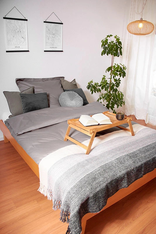 Decke aus brauner und weißer Alpakawolle auf einem Bett in einem Schlafzimmer. Dieses Bild ist ein Link, der zur Home-Produktseite führt.