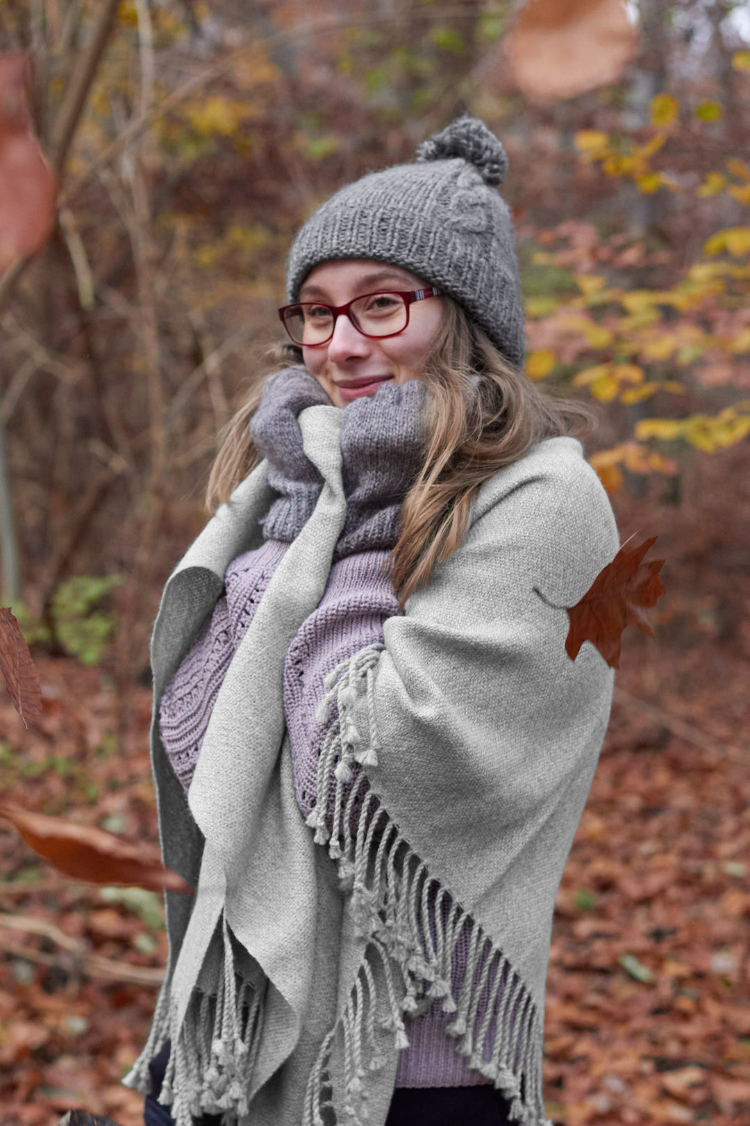 Blondes Model mit dem Alpaka-Poncho Osorno in warmer grauer Farbe.