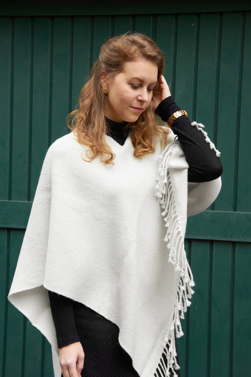 Blondes Model mit dem handgemachten Puyehue Alpaka-Poncho in weißer Farbe.