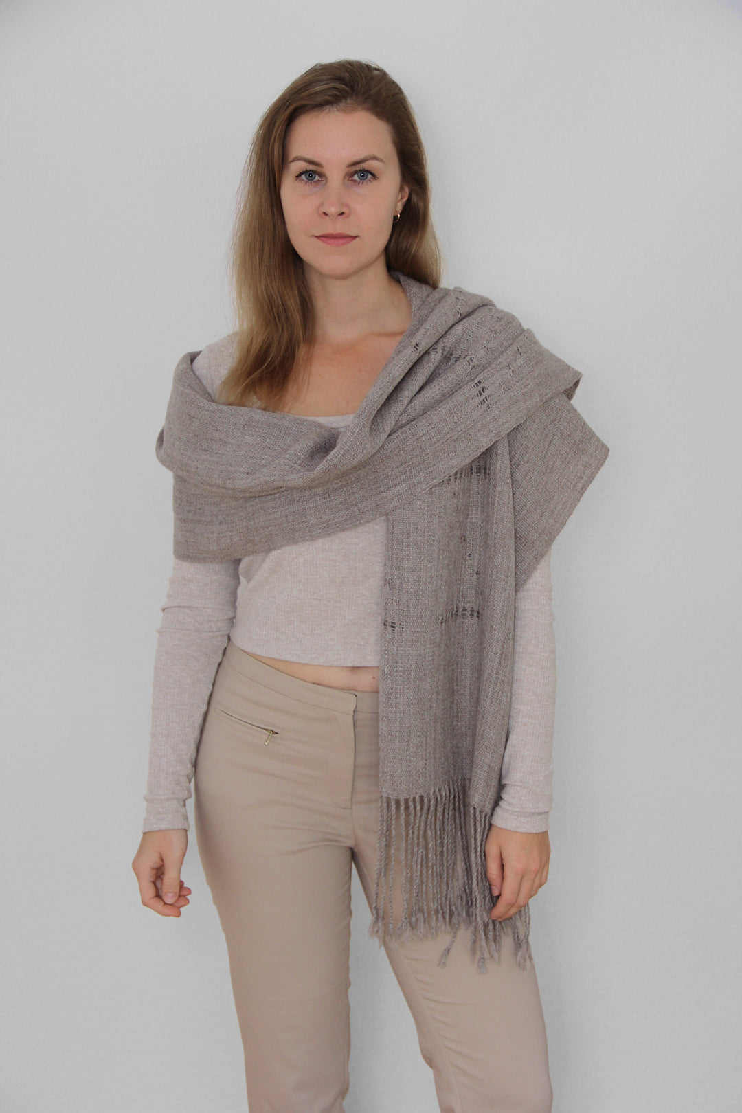 Ein Model mit einem bronzenen Schal aus Alpaka Wolle mit Lochmuster