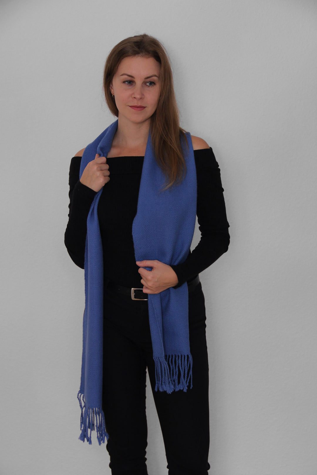 Blondes Model trägt den Miñiques Schal mit einfarbigem Muster in Blau.