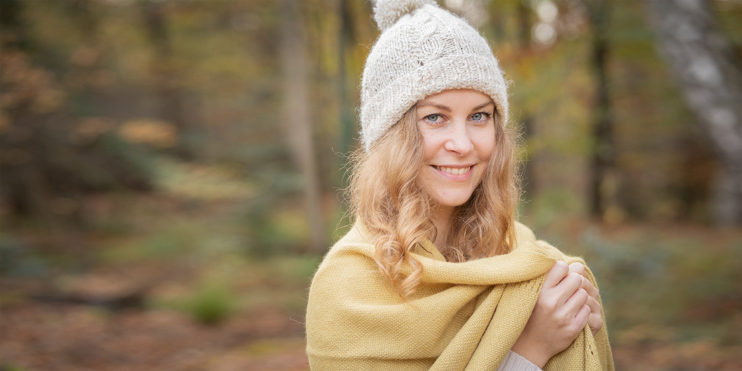 Blonde Frau mit weißer Mütze und gelbem Schal