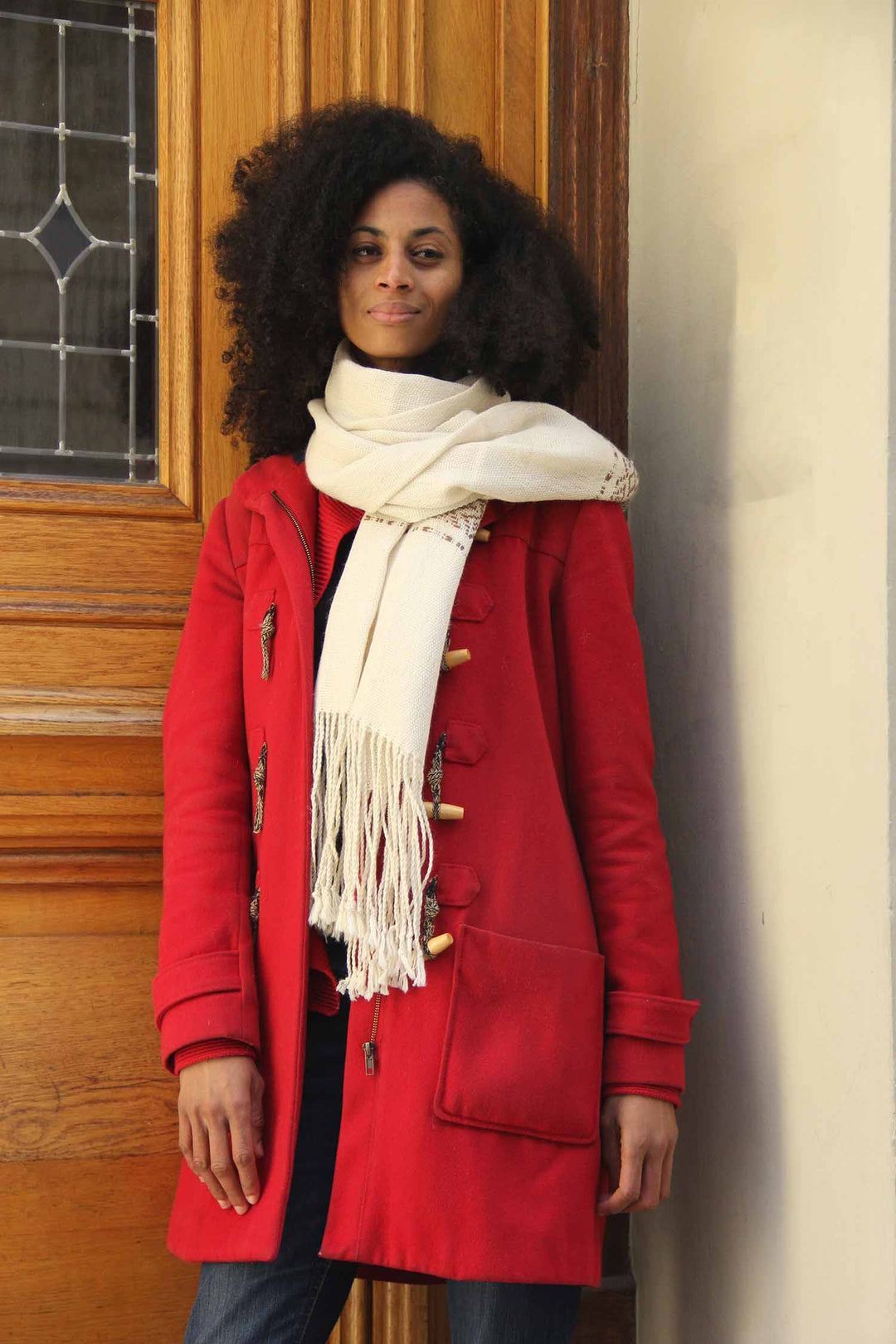 Afrikanische Frau mit einem weißen handgemachten Alpaka-Schal und einem roten Mantel.