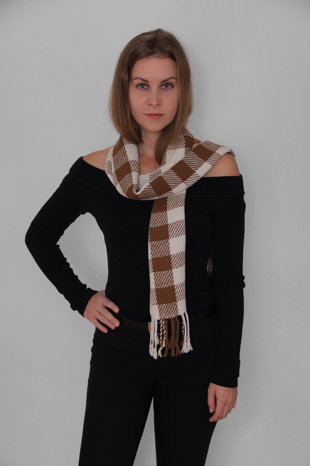 Blondes Model trägt einen karierten Schal aus Alpakawolle in braunen und weißen Farben. 3