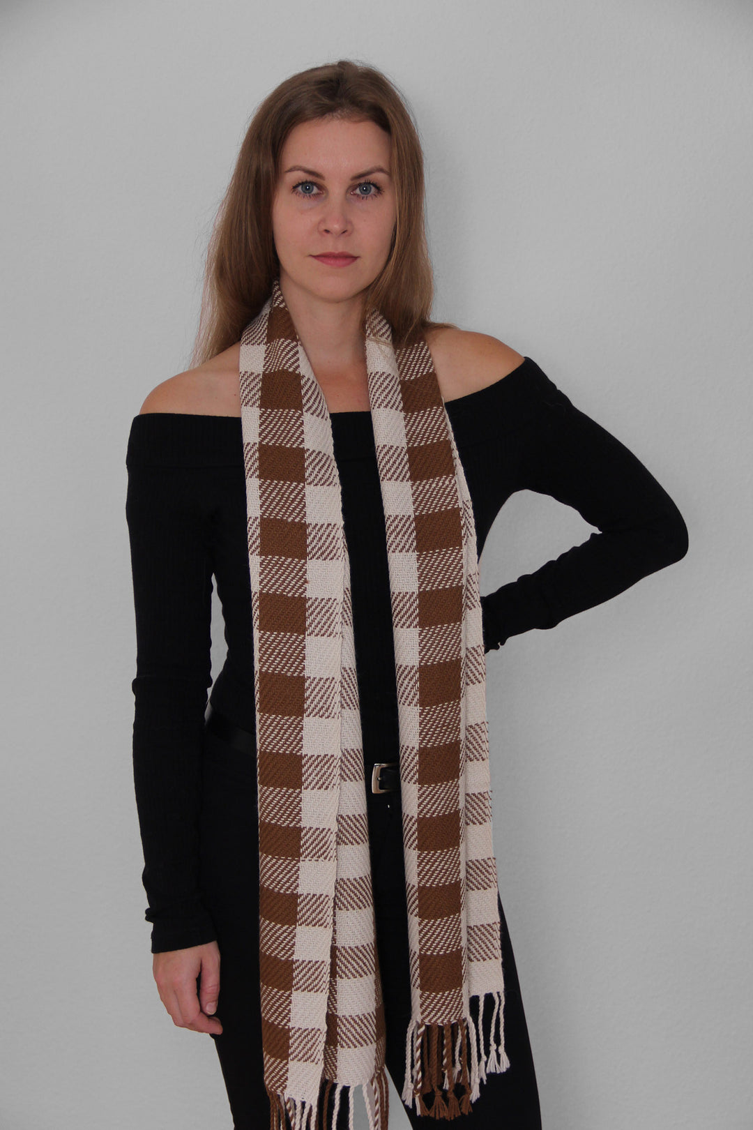 Blondes Model trägt einen karierten Schal aus Alpakawolle in braunen und weißen Farben. 2