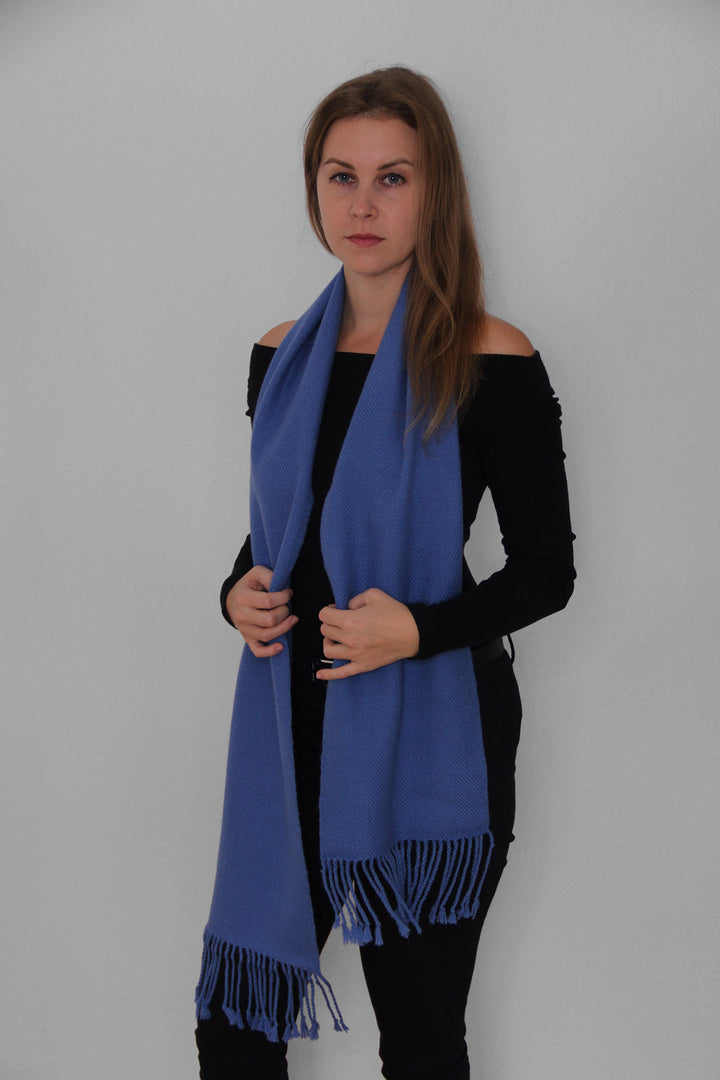 Blondes Model trägt den Miñiques Schal mit einfarbigem Muster in Blau.3