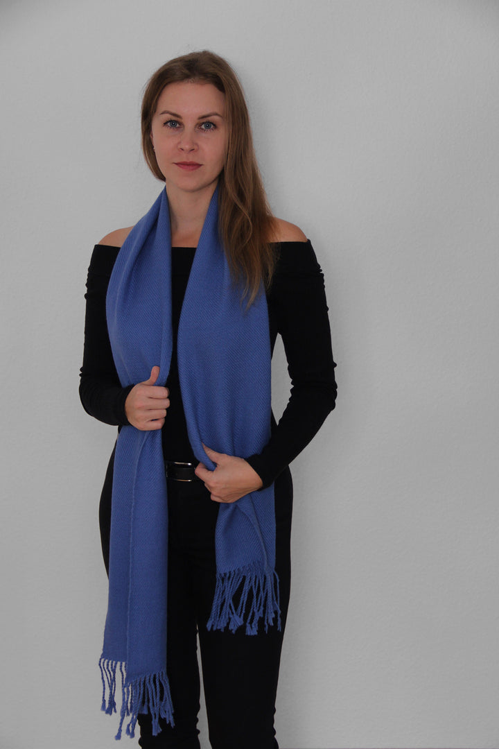 Blondes Model trägt den Miñiques Schal mit einfarbigem Muster in Blau.2